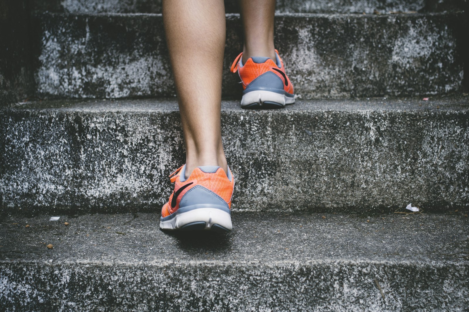 Running shoes climbing weathered concrete stairs